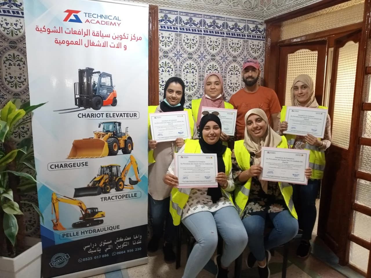 صورة جماعية لمشاركات حاملات شهادات بجانب لافتة الأكاديمية التقنية